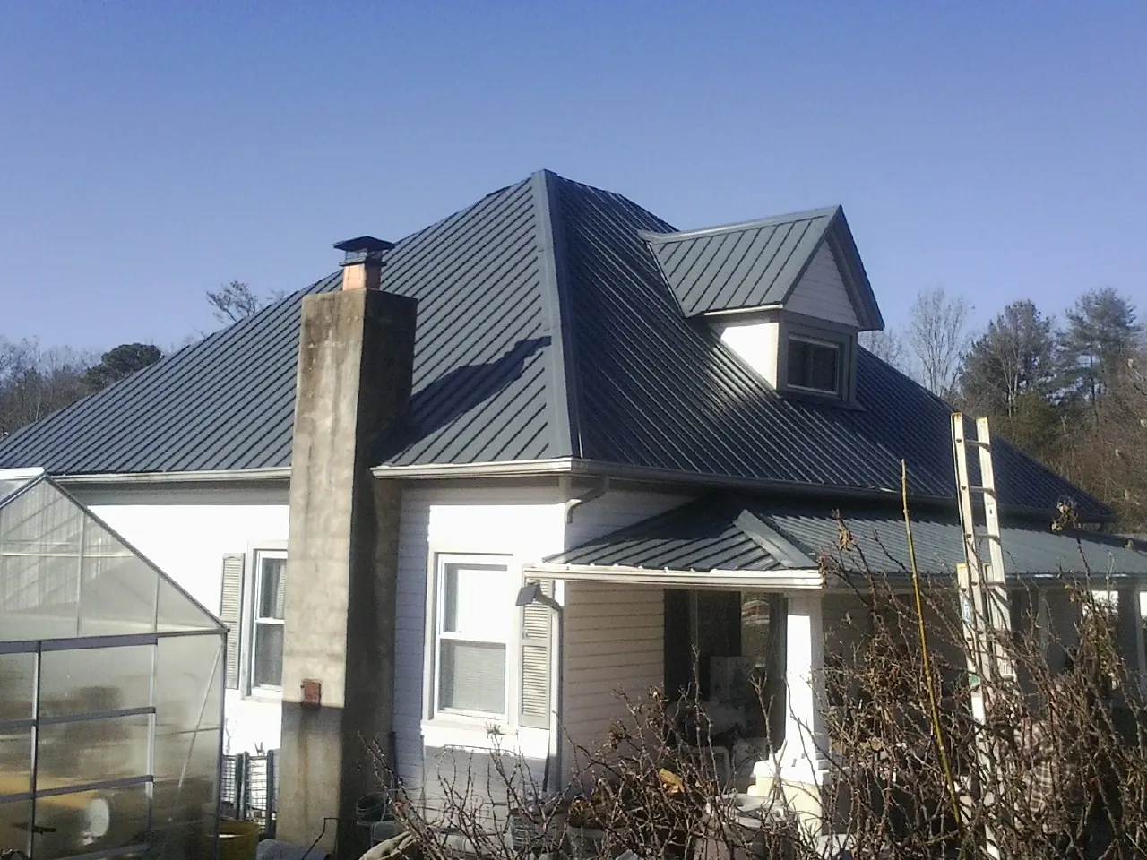 Dark blue standing seam metal roof on a white farmhouse with dormer — Slate & Tile Roof Repair by Roofing Brothers in Monee