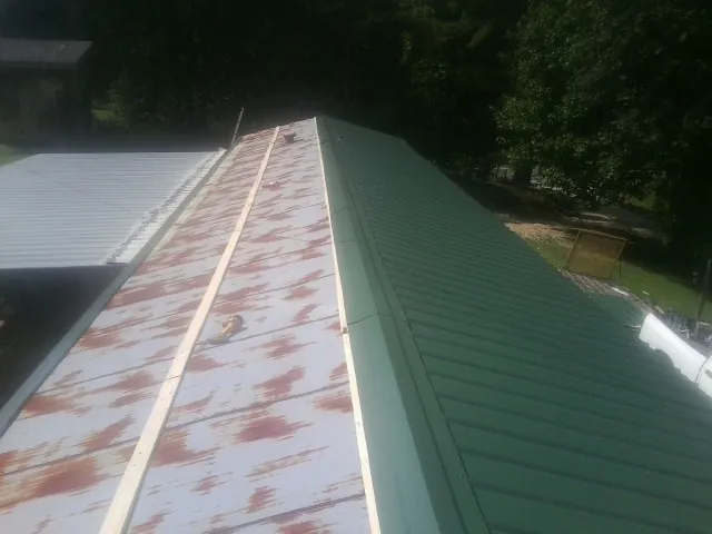 Old rusted panels beside newly installed green metal roofing — Wind Damage Roof Repair by Roofing Brothers in Monee