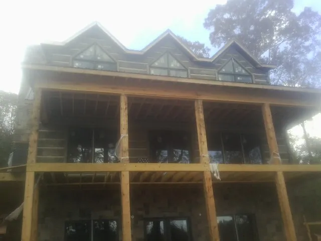 Dormers and porch framing on a large log home under construction — Roof Coating work by our crew in Monee
