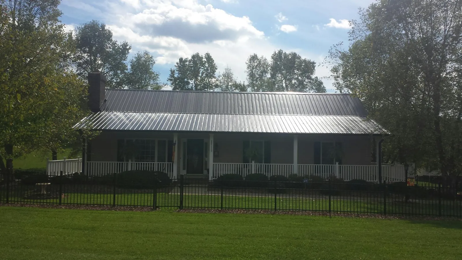 Gray metal roof on a brick ranch with a full width front porch — Gutter Guard Installation work by our crew in Monee