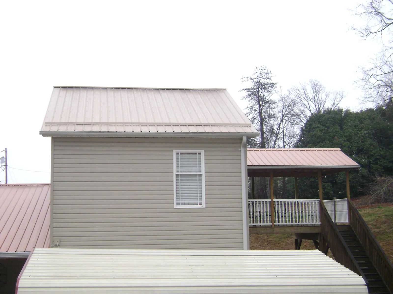 Tan metal roofs on a two story addition and attached porch, from a Roof Replacement job in Monee