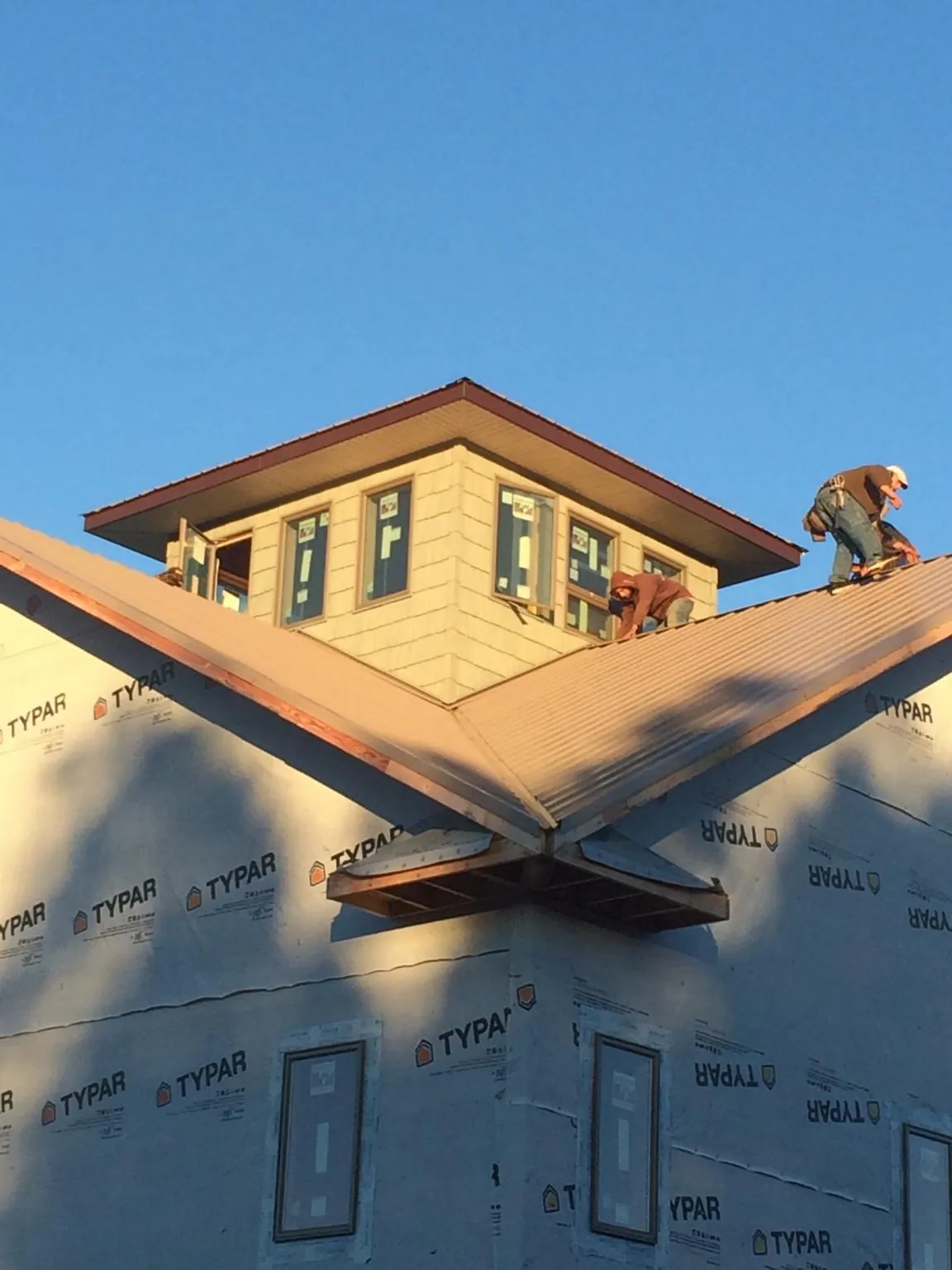 Roofers working around a rooftop cupola on a new metal roof at sunset — Roof Waterproofing in Monee by Roofing Brothers